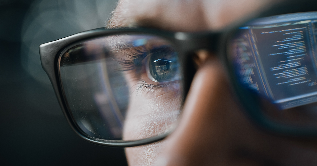 Man with glasses looking at screen with screen reflected back on lenses 